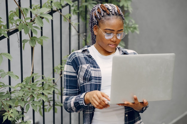 Photo gratuite fille noire dans une ville d'été avec ordinateur portable