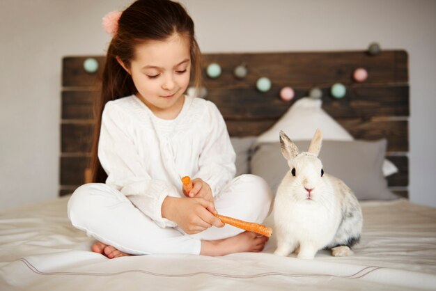 Fille nourrissant son lapin sur le lit