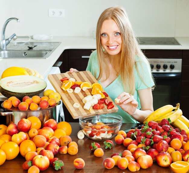 Fille ordinaire aux cheveux longs, cuisson de la salade de fruits