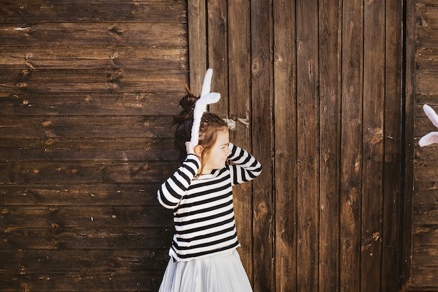 Fille avec des oreilles de lapin debout près du hangar