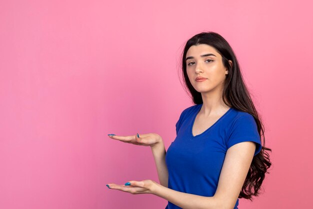 Fille paisible tenant ses mains ouvertes et regardant la caméra Photo de haute qualité