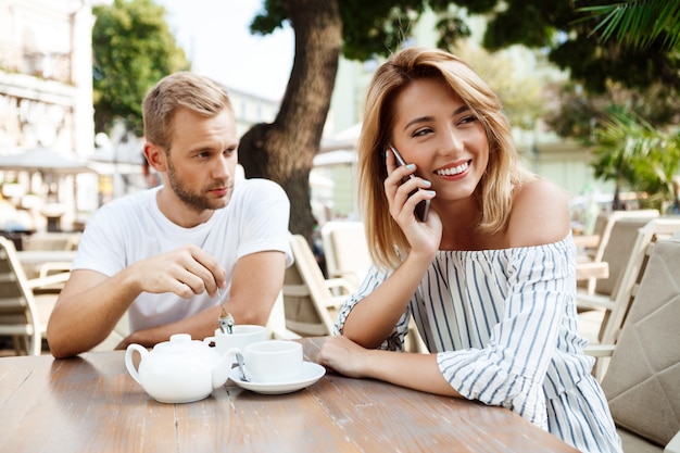 Fille parlant au téléphone pendant que son petit ami s'ennuie.