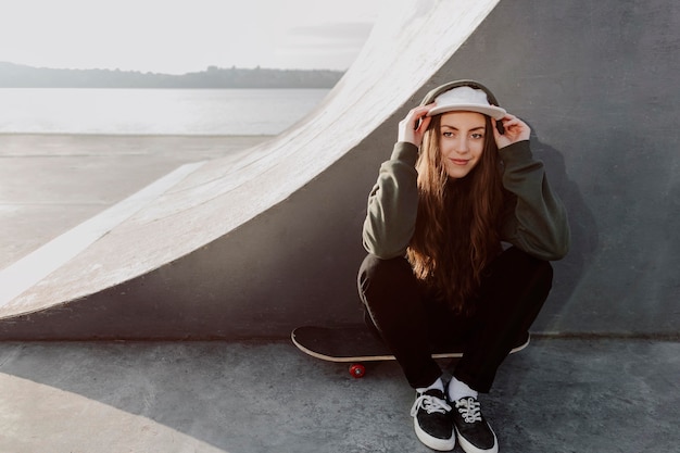 Photo gratuite fille de patineur vue avant assis à côté de la rampe