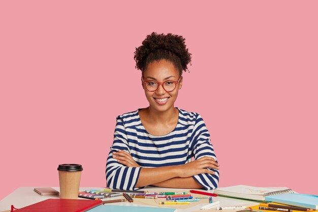 Fille à la peau sombre avec des cheveux bouclés peignés, a le sourire à pleines dents