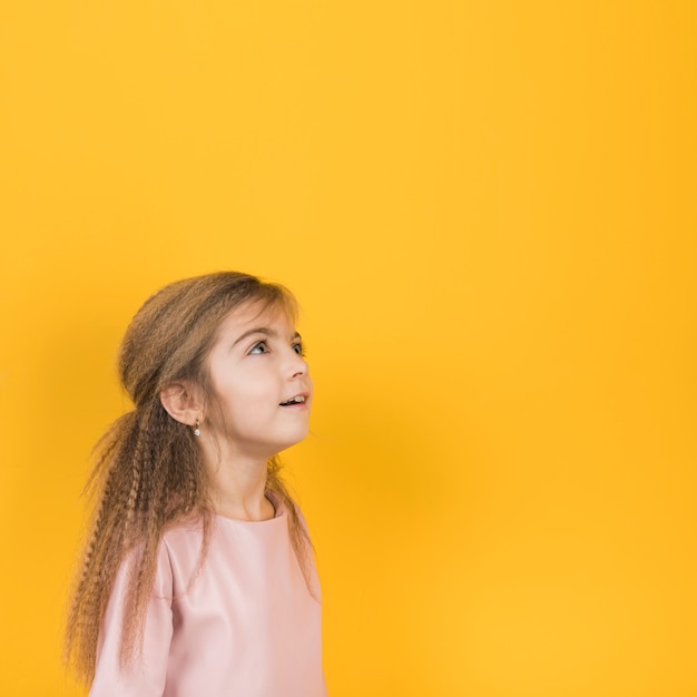 Fille pensive, levant sur fond jaune