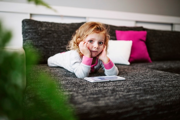 Fille pensive avec tablette en regardant la caméra