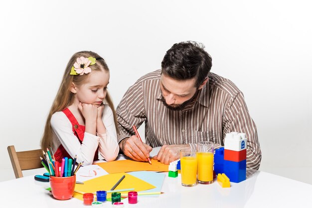 La fille et le père dessinent et écrivent ensemble sur fond blanc