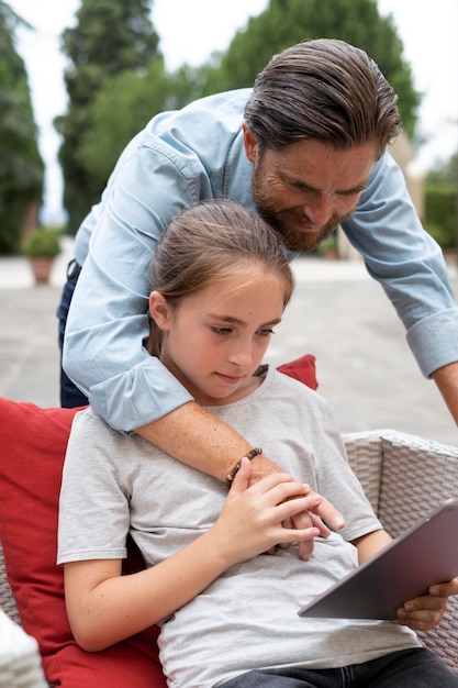 Fille et père de plan moyen avec tablette