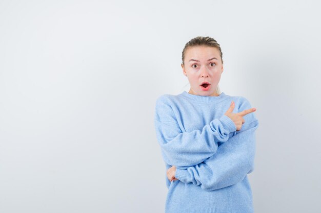 Fille perplexe montre son côté droit sur fond blanc