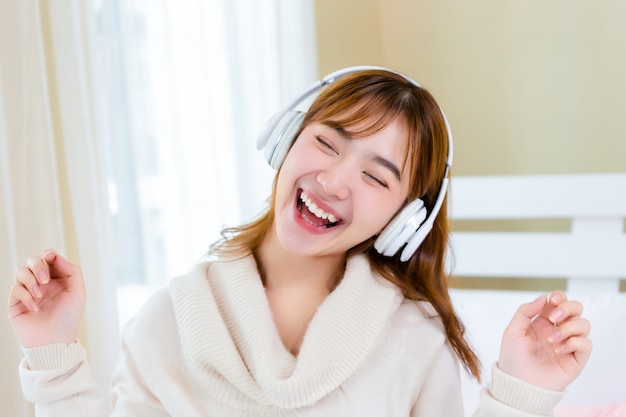 La fille portait des écouteurs et écoutait de la musique sur le lit.