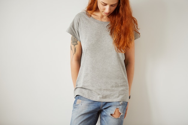 Fille portant un t-shirt blanc gris debout sur un mur blanc