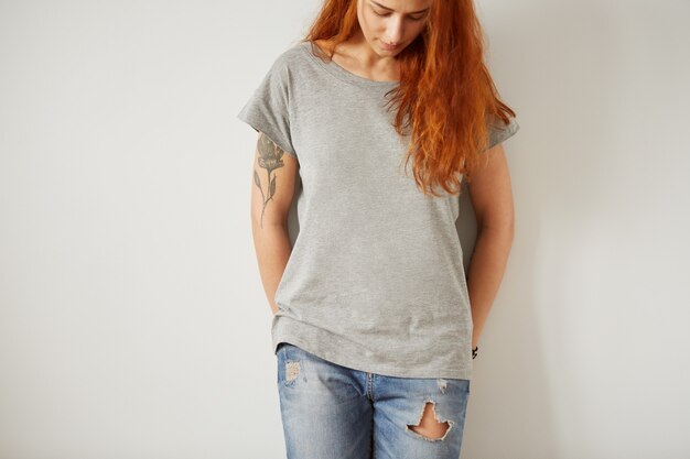 Fille portant un t-shirt blanc gris debout sur un mur blanc