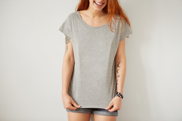 Photo gratuite fille portant un t-shirt blanc gris debout sur un mur blanc