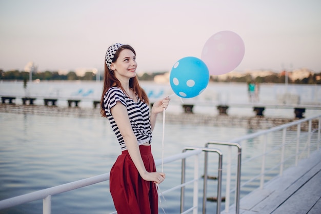 Fille posant avec des ballons dans un port