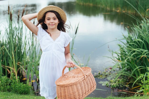 Fille posant avec un panier de pique-nique au bord du lac
