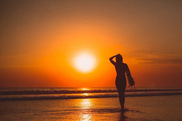 fille posant avec une planche au coucher du soleil