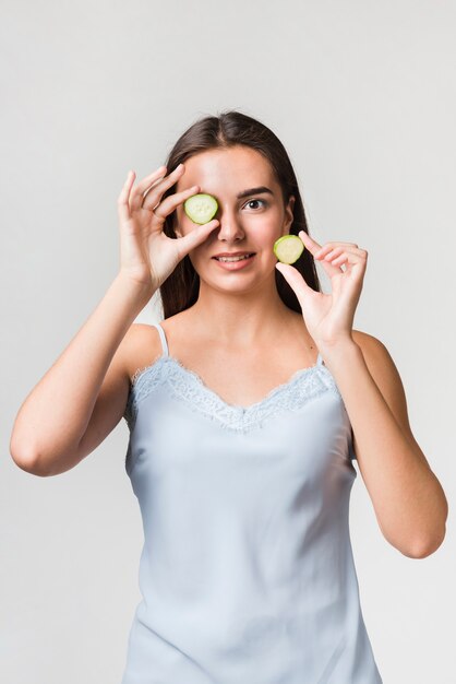 Fille posant avec des tranches de concombre