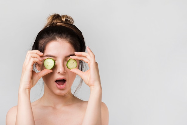 Fille posant avec des tranches de concombre