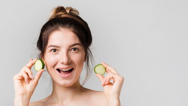 Fille posant avec des tranches de concombre