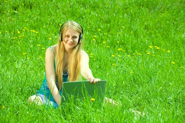 Fille sur la prairie avec un ordinateur portable