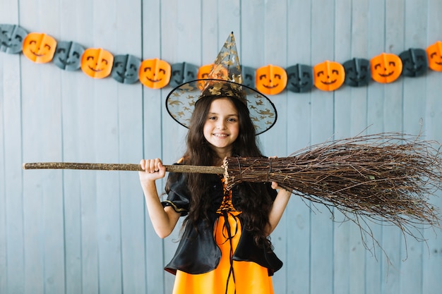 Fille préadolescente en costume d'Halloween tenant un balai