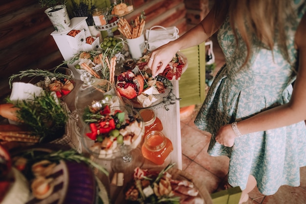 fille prend une tranche de fromage sur une table décorée avec des gâteaux