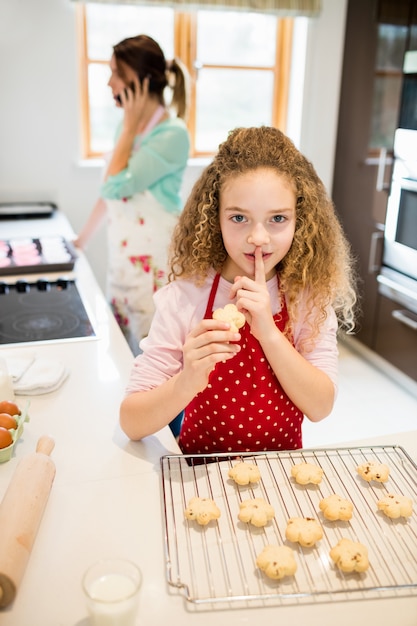 Fille de prendre les cookies secrètement pendant que la mère parler sur mobile