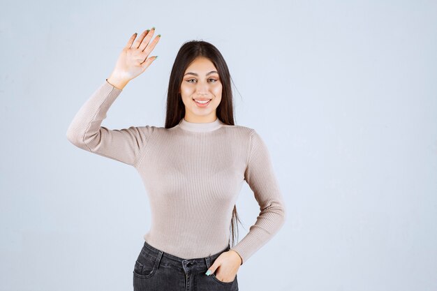 Fille en pull gris donnant des poses méchantes et séduisantes.