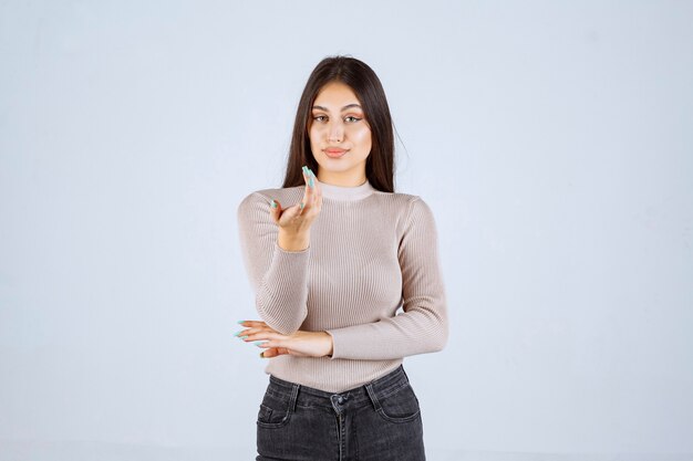 Fille en pull gris donnant des poses méchantes et séduisantes.