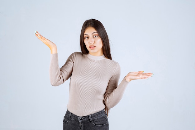 Fille en pull gris donnant des poses méchantes et séduisantes.