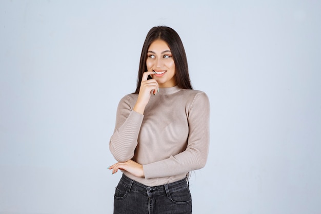 Fille en pull gris donnant des poses méchantes et séduisantes.