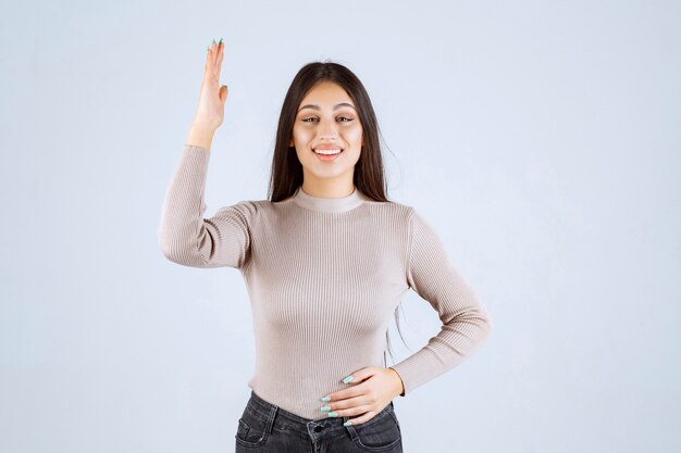 Fille en pull gris levant les mains.