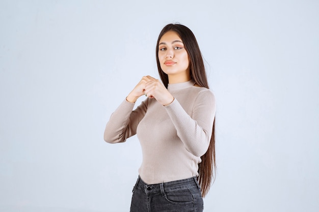 Fille en pull gris montrant ses poings et sa puissance.