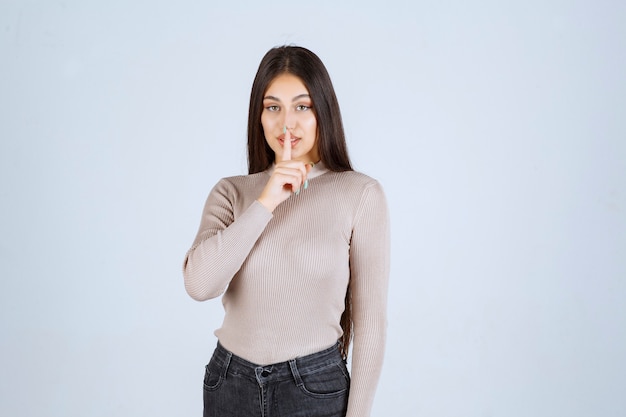 Fille en pull gris pointant quelque chose au-dessus.