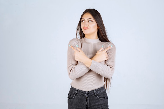 Fille en pull gris pointant quelque chose au-dessus.