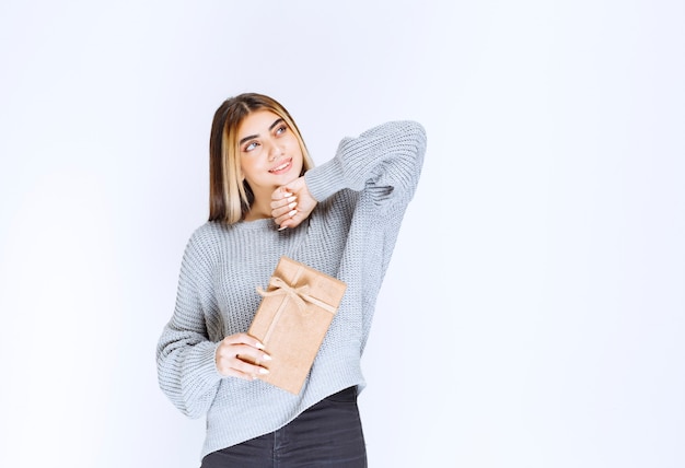 Fille En Pull Gris Tenant Une Boîte Cadeau En Carton.