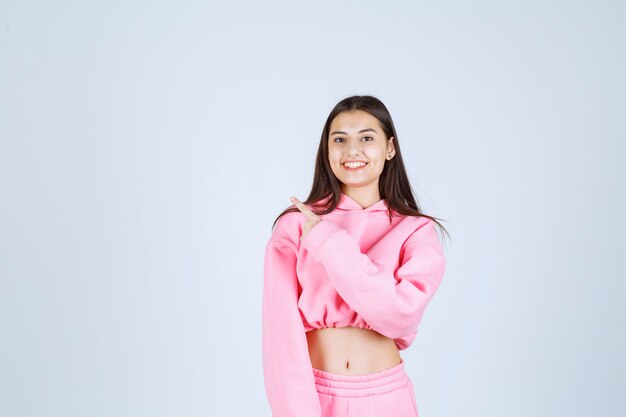 Fille en pyjama rose souriant et montrant l'arrière.