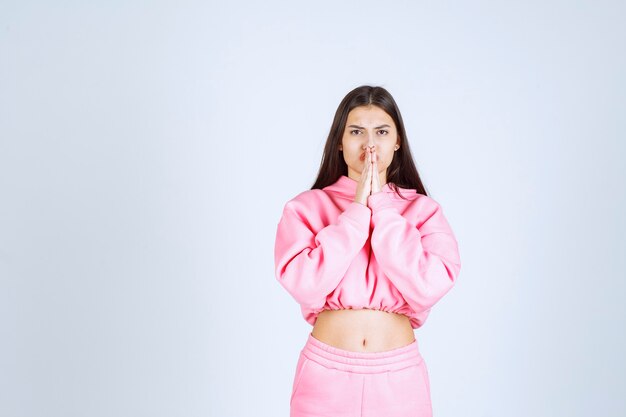 Fille en pyjama rose unissant ses mains et priant