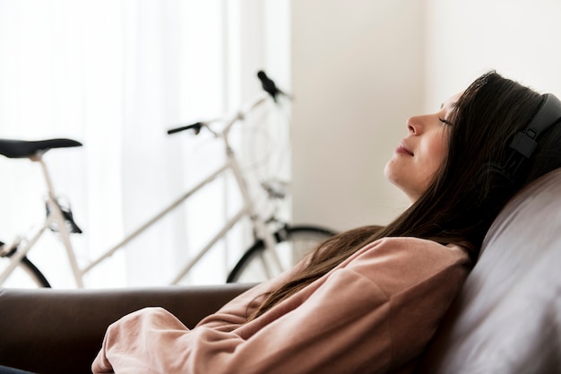 Fille qui écoute de la musique à la maison sur le canapé