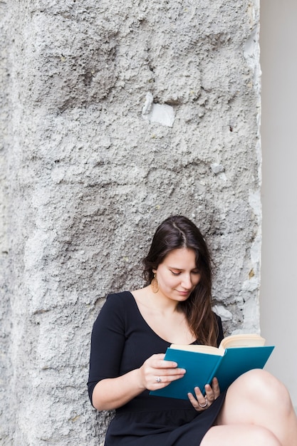 Une fille qui lit un livre dans la rue.