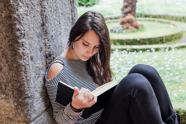 Une fille qui lit un livre dans la rue.
