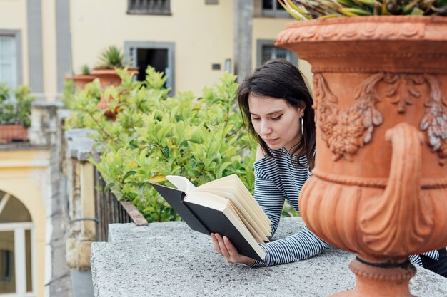 Une fille qui lit un livre dans la rue.