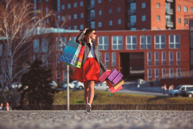 La fille qui marche avec du shopping dans les rues de la ville