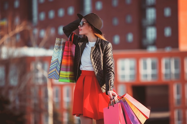 La fille qui marche avec des sacs à provisions dans les rues de la ville à la journée ensoleillée