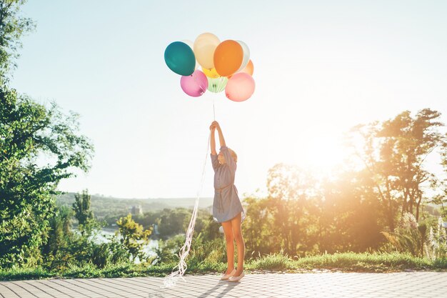 Fille qui s'étend aux ballons colorés