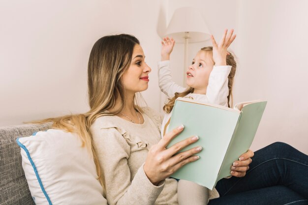 Fille racontant une histoire à maman en lisant un livre