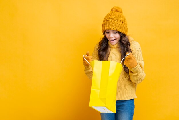 Fille à la recherche dans un sac shopping jaune