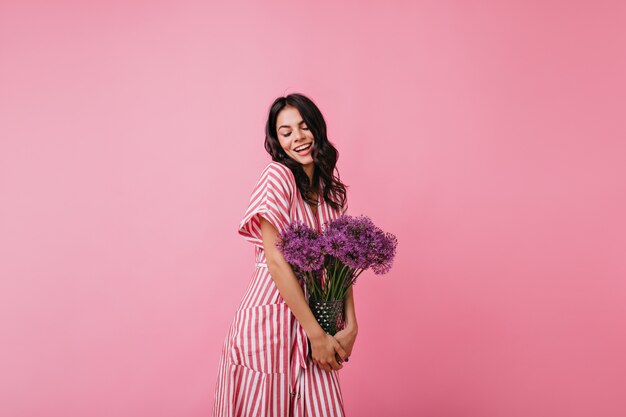 La fille a reçu des fleurs en cadeau et se réjouit. Portrait de brune d'humeur romantique.