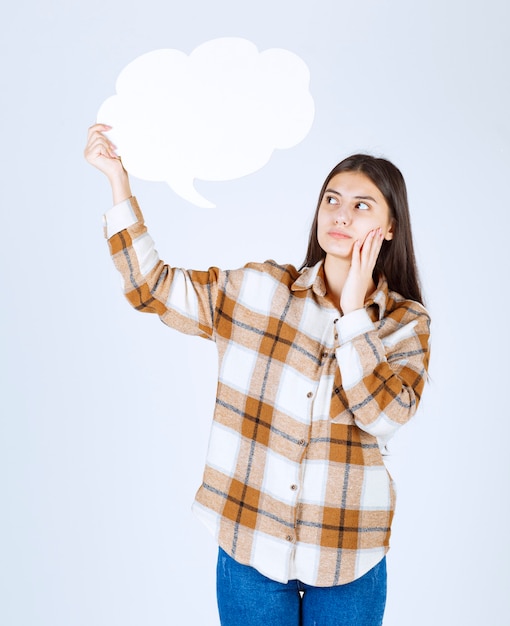 fille réfléchie regardant un nuage de texte vide sur un mur blanc.