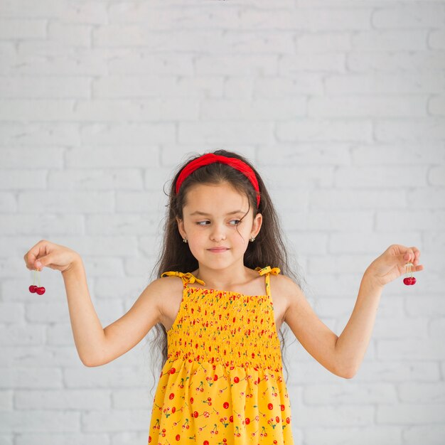 Fille regardant les cerises rouges tenant dans ses mains